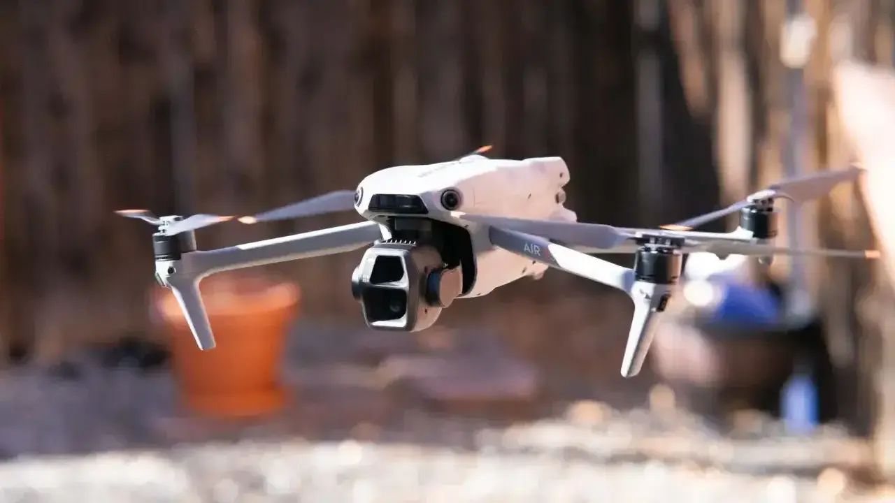 Biały dron Mavic Air w locie, z widocznymi śmigłami i kamerą.