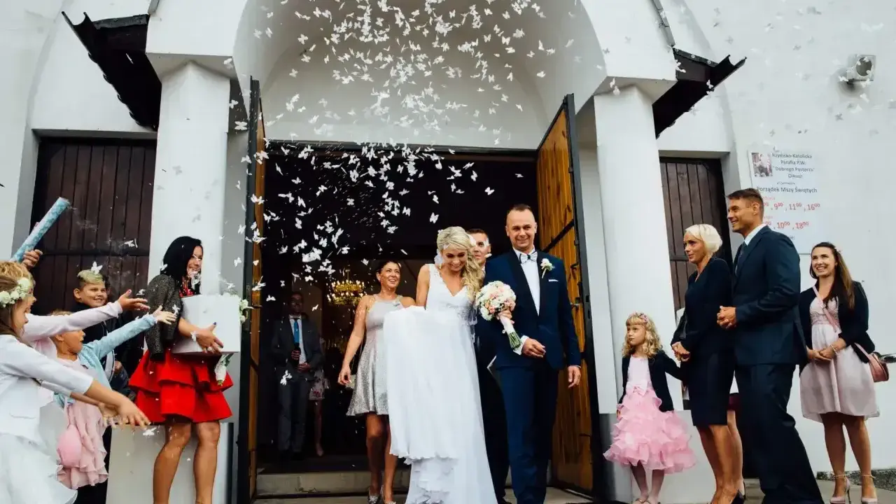 Para młoda wychodzi z kościoła, obsypana płatkami. Piękny moment z polskich wesel.