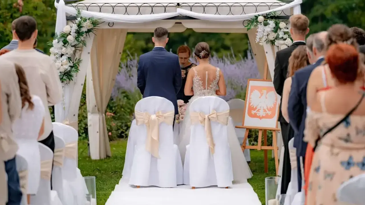Para młoda podczas ceremonii ślubnej. Wesele w plenerze, pod namiotem ozdobionym kwiatami.