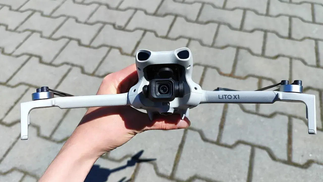 Ręka trzyma najnowszy dron DJI, gotowy do lotu. Jego kompaktowa konstrukcja i zaawansowana kamera zapowiadają niesamowite ujęcia.