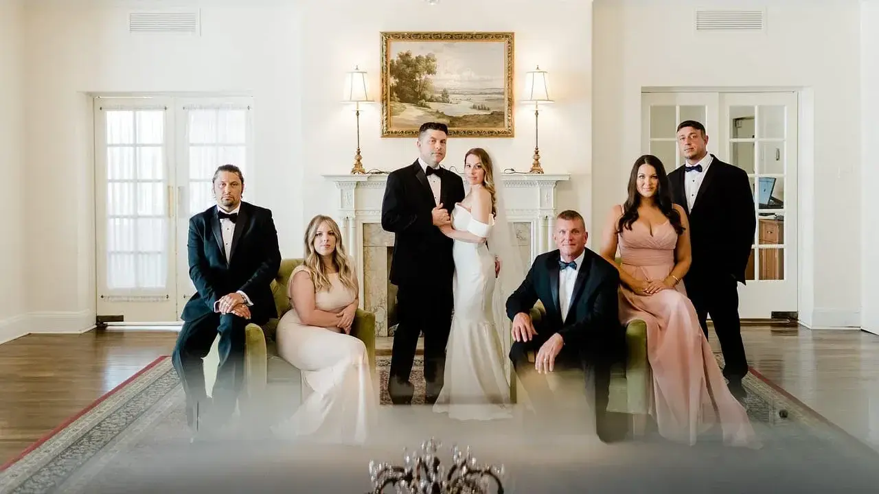 Para młoda z rodziną pozuje do zdjęcia przed ślubem. Eleganckie stroje i uroczysta atmosfera.