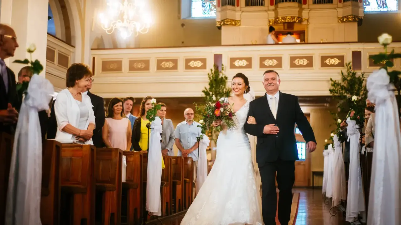 Panna młoda z bukietem idzie do ołtarza z ojcem. Cichy ślub kościelny bez mszy, w kościele pełnym gości.