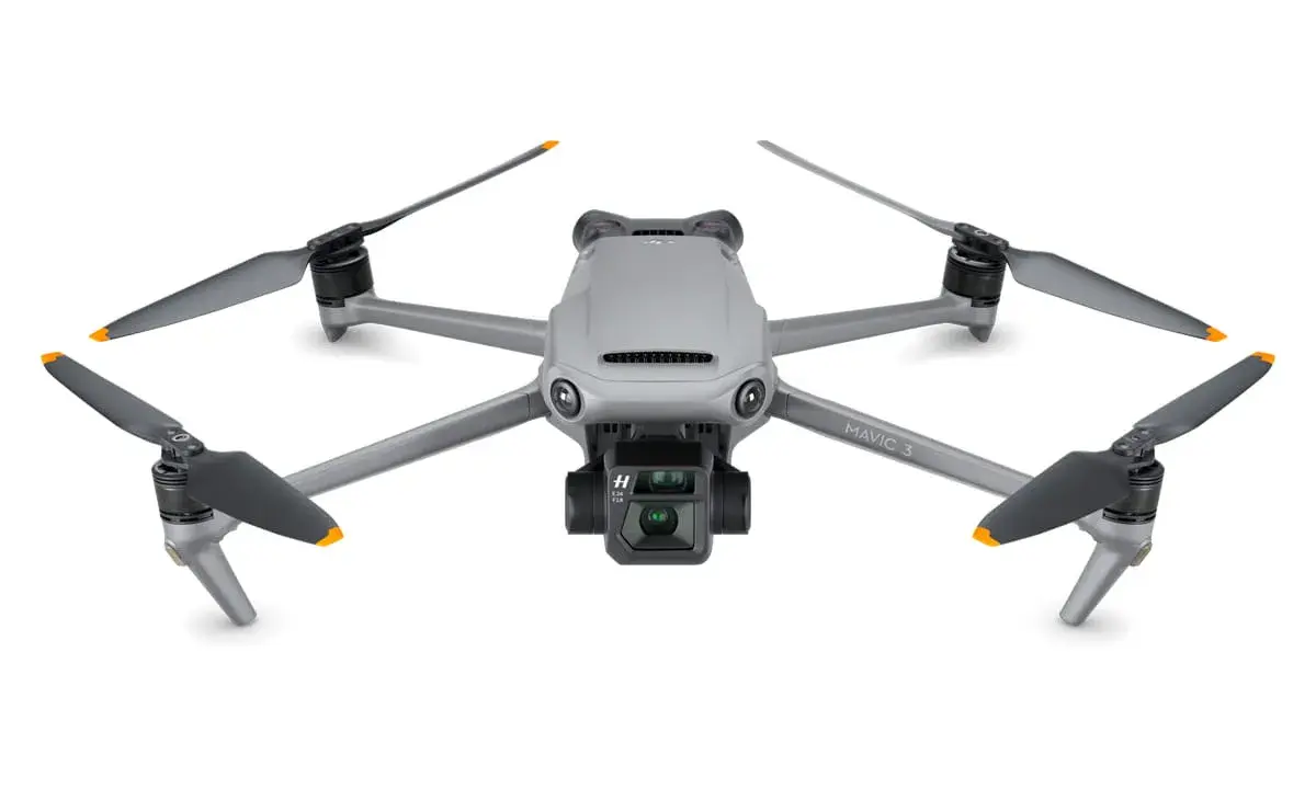 Szary dron DJI Mavic 3 z kamerą i czterema śmigłami. Jego niewielka waga pozwala na długie loty.
