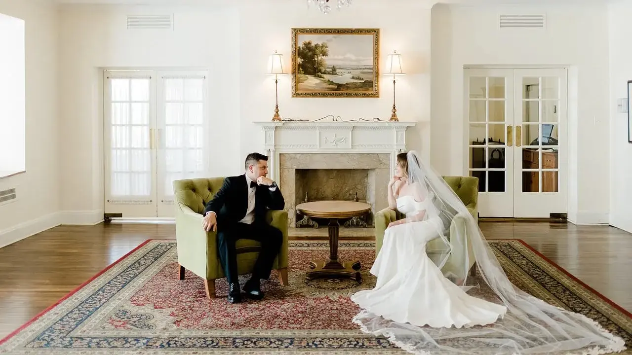 Para młoda siedzi naprzeciwko siebie w eleganckich fotelach. Widać, co daje ślub: spokój i wzajemne spojrzenie.