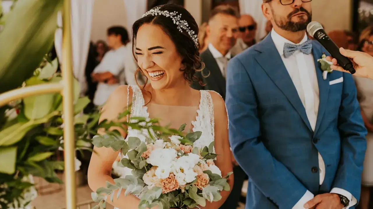 Szczęśliwa panna młoda z bukietem, obok pana młodego w garniturze. Ceremonia ślubu cywilnego, konsekwencje tej decyzji są radosne.