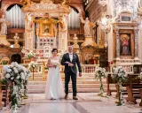 Para młoda idzie do ołtarza podczas ślubu w Rzymie. Wspaniała bazylika, ozdobiona kwiatami i organami, tworzy magiczną atmosferę.