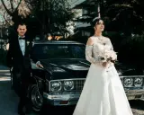 Para, w eleganckim czarnym garniturze, i panna młoda w sukni z koronki, z bukietem w dłoni, stoją obok zabytkowego samochodu. Nawet jeśli nie mam świadków na ślub, ten dzień jest nasz.