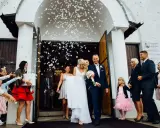 Para młoda wychodzi z kościoła, obsypana płatkami. Piękny moment z polskich wesel.