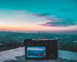 Aparat fotograficzny na tle miejskiego krajobrazu o zachodzie słońca. Różnorodne rodzaje światła tworzą magiczną atmosferę.