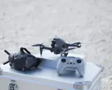 Szybkie drony, gogle FPV i kontroler gotowe do akcji na plaży.