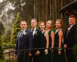 Pan młody i jego drużba, ubrani w garnitury, stoją obok druhen w zielonych sukniach. To idealna drużyna, która wie, co potrzebuje świadek do ślubu kościelnego.