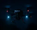 Policyjny dron nocą, z niebieskimi i czerwonymi światłami, gotowy do akcji.