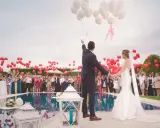 Para młoda wypuszcza balony, goście świętują wesele w piątek.