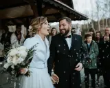 Szczęśliwa para młoda, trzymająca bukiet, wychodzi na zewnątrz podczas swojego ślubu w Adwencie. Sypią się na nich płatki.