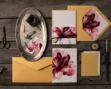 Eleganckie zaproszenia DIY z motywem kwiatowym, złote koperty, nożyczki, kluczyk i kałamarz.