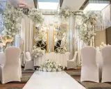 Eleganckie przyjęcie po ślubie cywilnym. Białe kwiaty, złote lustra i białe pokrowce na krzesłach tworzą romantyczną atmosferę.