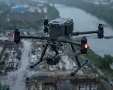 Profesjonalny dron z kamerą w locie podczas ulewy nad placem budowy.
