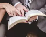 Dłonie pary wskazują na tekst w Biblii, przygotowując się do wspólnych czytań na ślubie.