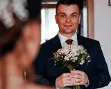 Młody mężczyzna w garniturze trzyma bukiet róż. Czy były ksiądz może wziąć ślub kościelny? To pytanie, które nurtuje wielu.