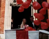 Para młoda wychodzi z kościoła w pudełku, otoczona czerwonymi balonami w kształcie serc. Wspaniałe pomysły na wesele niespodzianki!