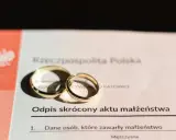 Złote obrączki na odpisie skróconym aktu małżeństwa po ślubie cywilnym.