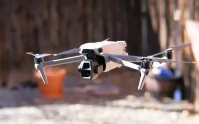 Biały dron Mavic Air w locie, z widocznymi śmigłami i kamerą.
