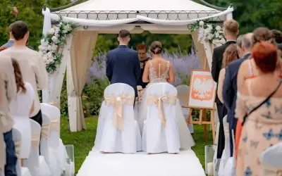 Para młoda podczas ceremonii ślubnej. Wesele w plenerze, pod namiotem ozdobionym kwiatami.