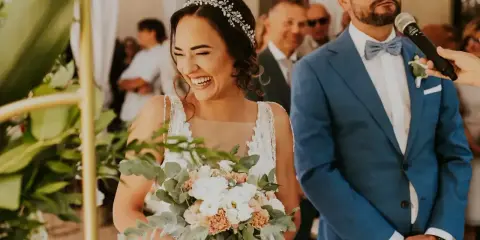 Szczęśliwa panna młoda z bukietem podczas ślubu cywilnego. Pan młody w niebieskim garniturze stoi obok.