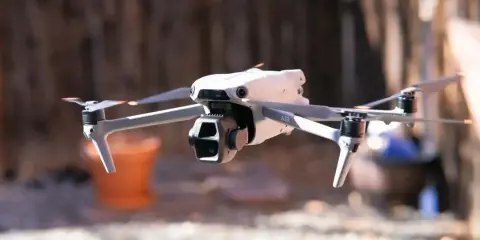Biały dron Mavic Air w locie, z widocznymi śmigłami i kamerą.