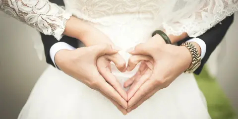 Serce z dłoni symbolizuje błogosławieństwo przed ślubem cywilnym. Panna młoda w koronkowej sukni i pan młody w garniturze tworzą ten piękny gest.
