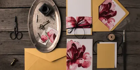 Eleganckie zaproszenia DIY z motywem kwiatowym, złote koperty, nożyczki, kluczyk i kałamarz.