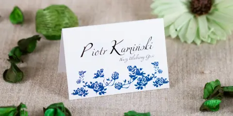 Winietka z imieniem "Piotr Kamiński" i napisem "Nasz Ulubiony Gość", ozdobiona niebieskimi różami. Idealna jako osoba towarzysząca.