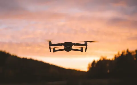 Dron w locie na tle zachodzącego słońca. Jego zasięg pozwala na uchwycenie pięknych krajobrazów.