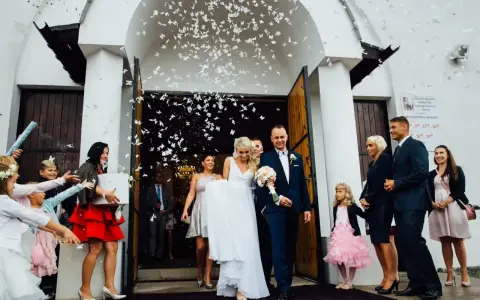 Para młoda wychodzi z kościoła, obsypana płatkami. Piękny moment z polskich wesel.