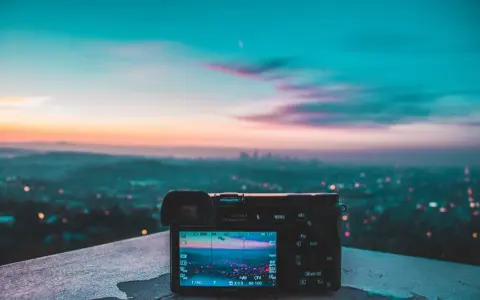 Aparat fotograficzny na tle miejskiego krajobrazu o zachodzie słońca. Różnorodne rodzaje światła tworzą magiczną atmosferę.