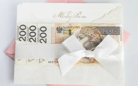 Biała koperta z napisem "Młodej Parze" i banknotami 200 zł. Zastanawiasz się, ile się daje na wesele? Oto inspiracja!