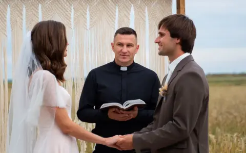 Para młoda trzyma się za ręce, a ksiądz błogosławi ich w dniu ślubu. Kiedy płaci się księdzu za ślub, ważne jest, by pamiętać o tej uroczystej chwili.