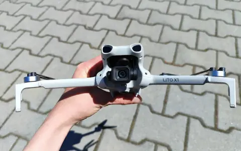 Ręka trzyma najnowszy dron DJI, gotowy do lotu. Jego kompaktowa konstrukcja i zaawansowana kamera zapowiadają niesamowite ujęcia.