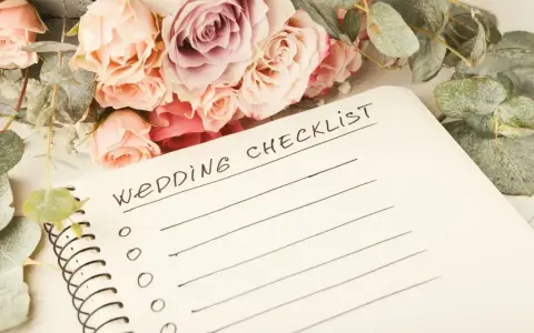 Bukiet róż i eukaliptusa obok notatnika z napisem "Wedding Checklist". Idealna inspiracja, co zabrać na wesele.