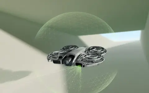DJI NEO 2 Fly More Combo w locie, otoczony siatką bezpieczeństwa, emituje zielone światło.