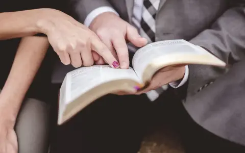 Dłonie pary wskazują na tekst w Biblii, przygotowując się do wspólnych czytań na ślubie.