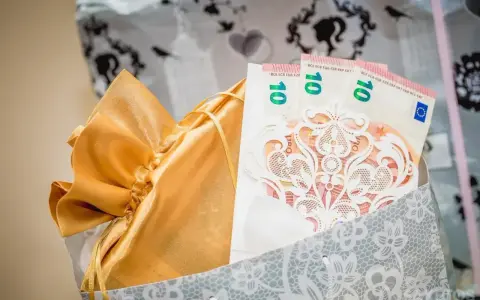 Elegancki sposób na to, jak zapakować pieniądze na ślub: banknoty 10 euro w ozdobnej kopercie, w złotej sakiewce, w ozdobnej torbie.
