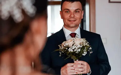 Młody mężczyzna w garniturze trzyma bukiet róż. Czy były ksiądz może wziąć ślub kościelny? To pytanie, które nurtuje wielu.