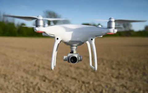 Biały dron DJI Phantom 4 Pro w locie nad polem.
