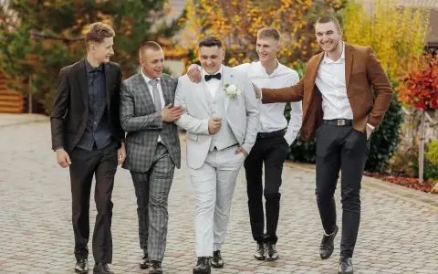 Pięciu panów w garniturach, idealnie dobranych na ślub. Pan młody w jasnym, koledzy w ciemniejszych stylizacjach.