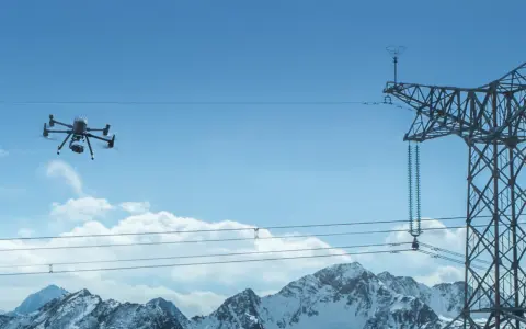 Dron Matrice 300 RTK w locie, inspekcja linii energetycznych nad ośnieżonymi górami.