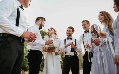 Pan młody i świadek świętują z panną młodą i druhnami. Wszyscy uśmiechnięci, w rękach kieliszki i butelka szampana.