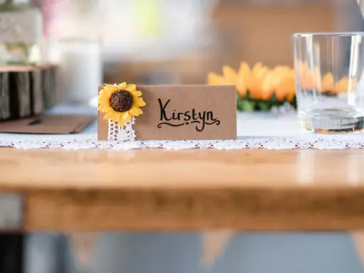 Urocza winietka z imieniem "Kirstyn" i słonecznikiem. Proste i stylowe, idealne, by pokazać, jak zrobić winietki na przyjęcie.