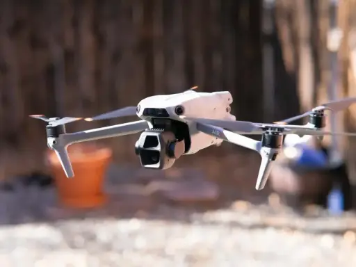Biały dron Mavic Air w locie, z widocznymi śmigłami i kamerą.