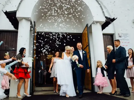 Para młoda wychodzi z kościoła, obsypana płatkami. Piękny moment z polskich wesel.
